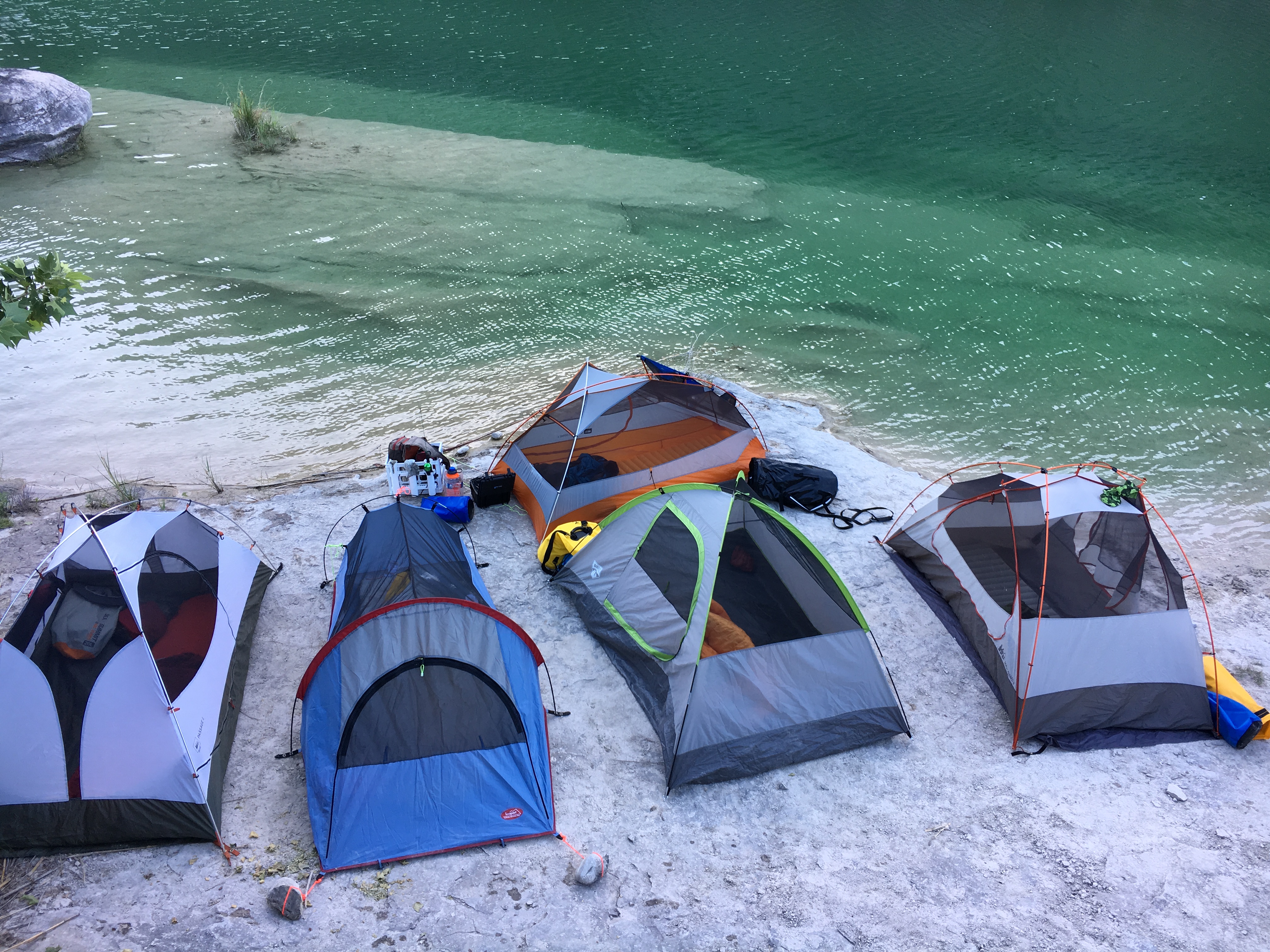 Five tents on the white limestone sandbar — the whole crew camped right on the water's edge